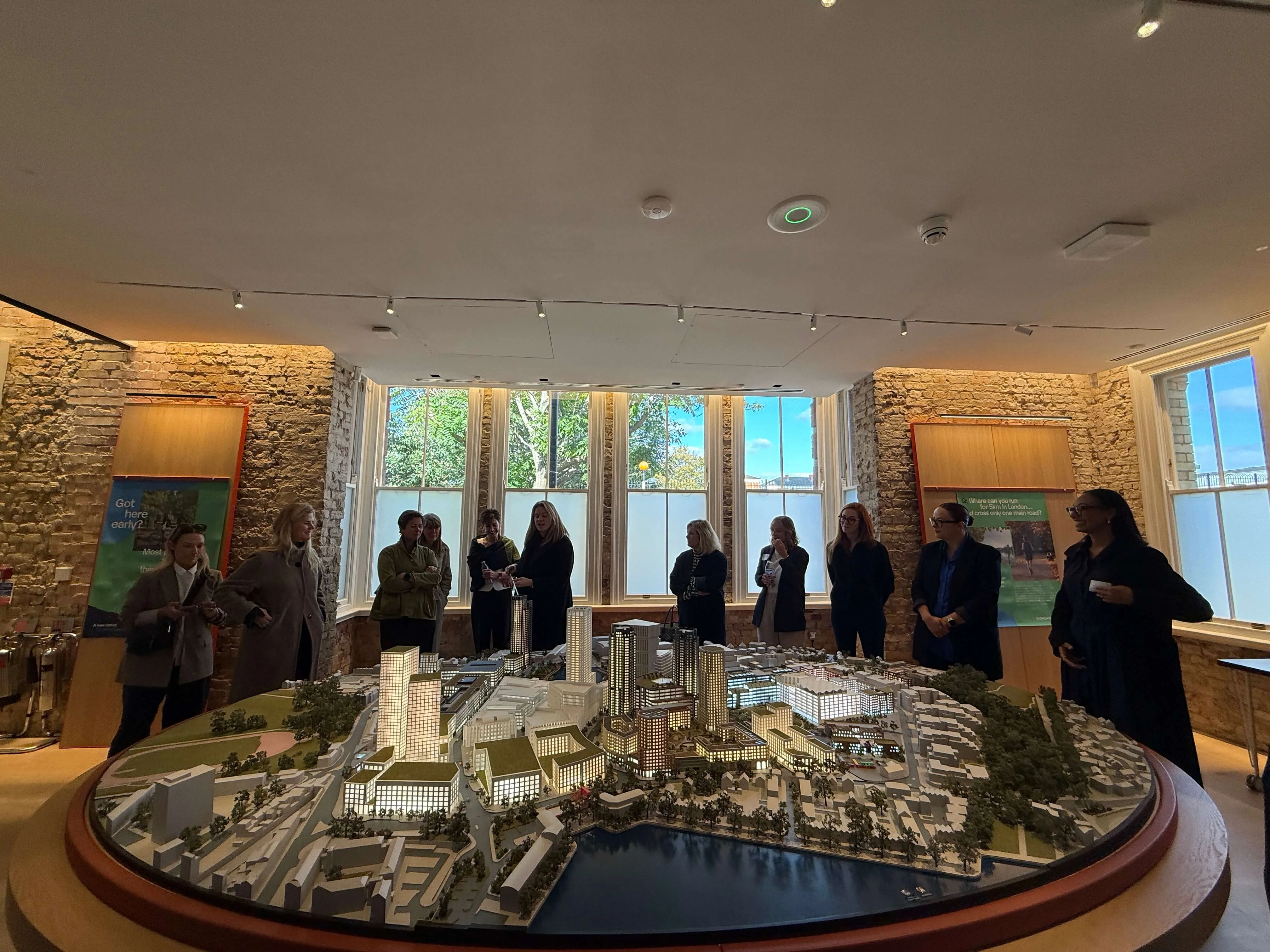 Image of a group of people standing in a circle looking at a model of a city